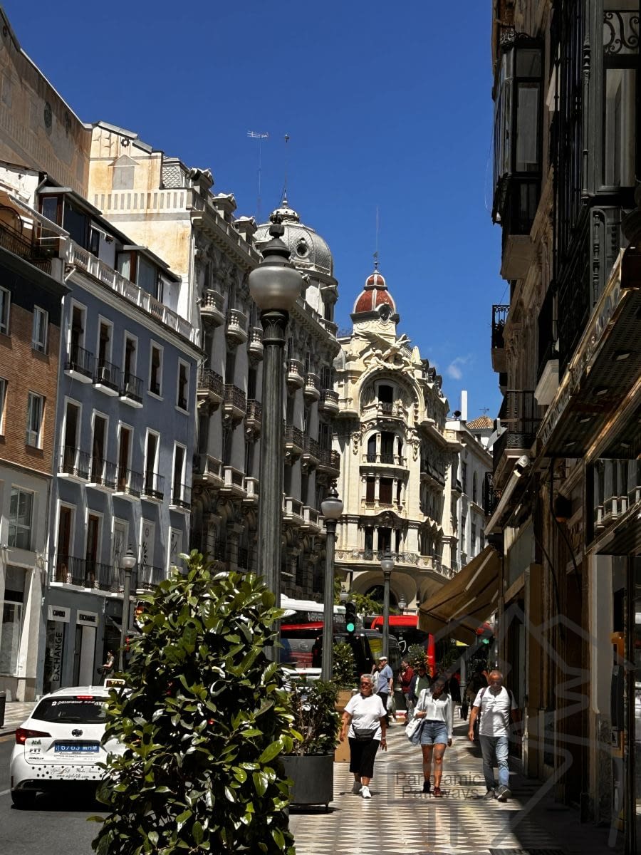 Street in Granada&rsquo;s historic center with traditional buildings and pedestrians.