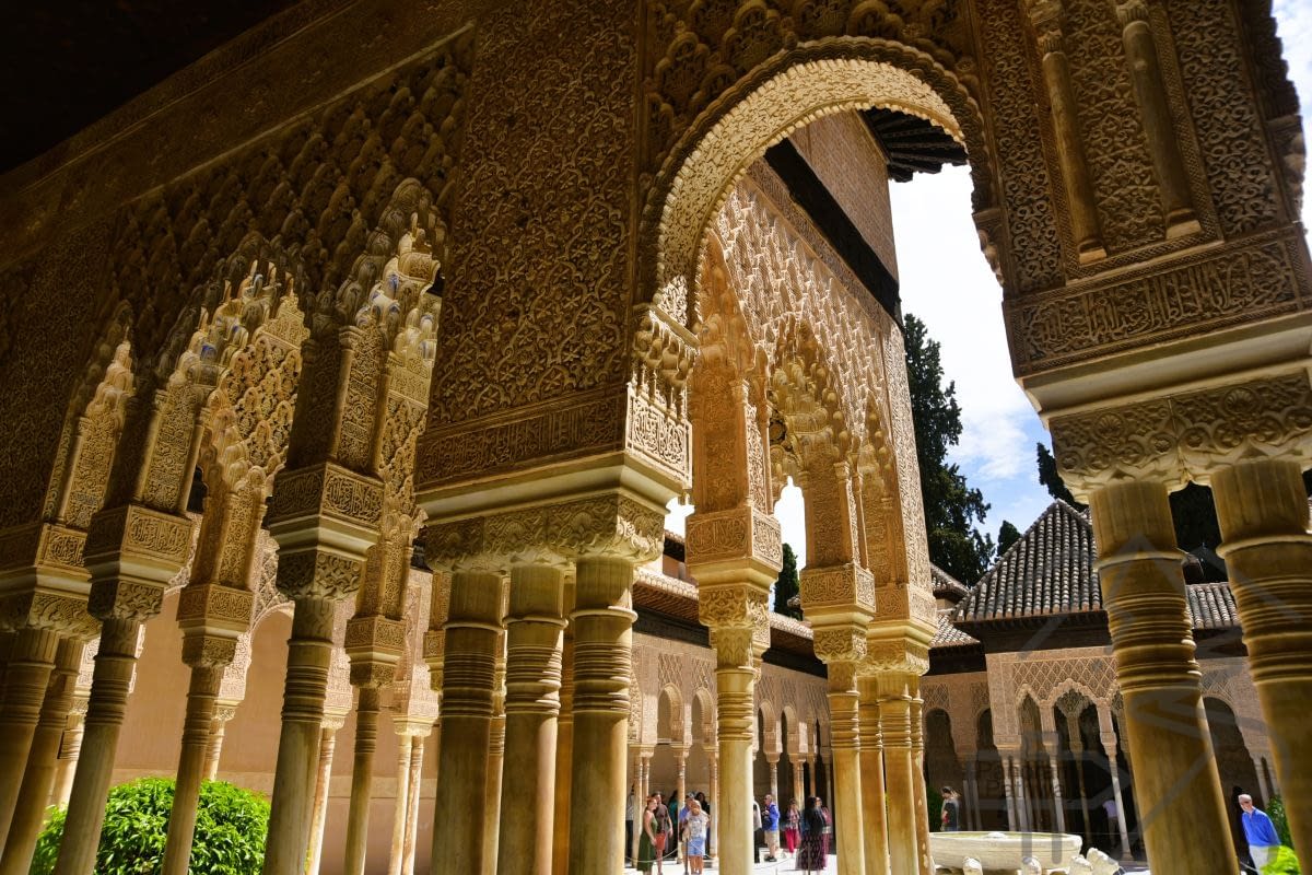 Detail view inside the Alhambra showing Islamic architectural patterns and ornate stonework.