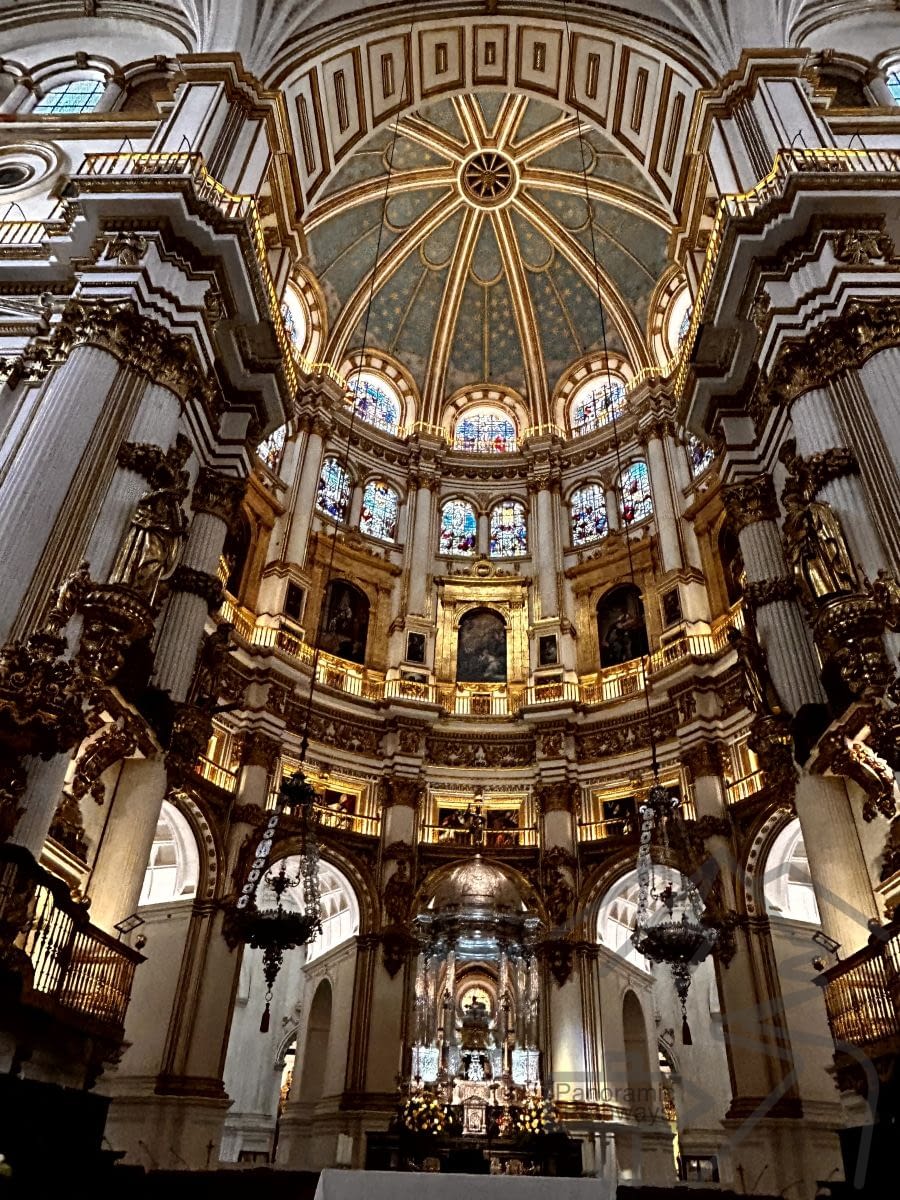 Interior of Granada Cathedral with soaring white columns and a bright nave.